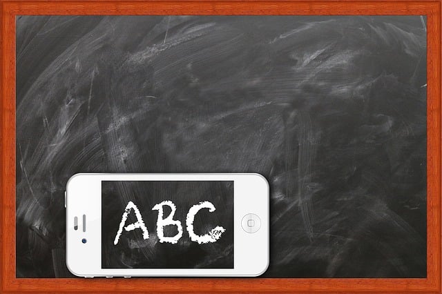 Ein Smartphone liegt vor einer Kreidetafel mit Holzrahmen. Auf dem Bildschirm des Smartphones ist in weißer Kreideschrift ‘ABC’ zu sehen – die Schrift passt optisch zur Tafel. Symbolbild für digitales Lernen oder Medienbildung in der Schule.